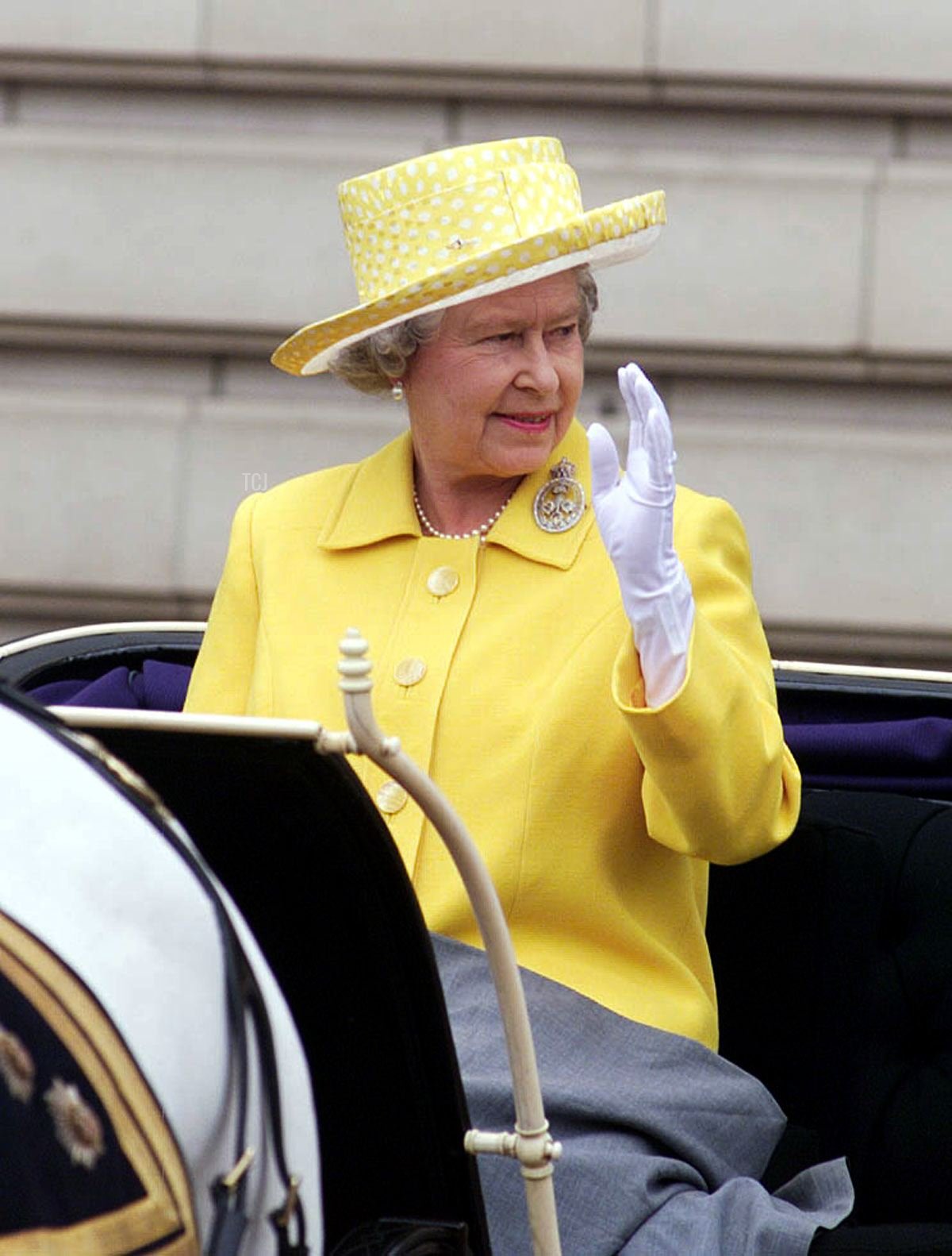 La Regina Elisabetta II saluta le folle mentre viaggia in una carrozza aperta verso la cerimonia del Trooping the Colour a Londra, il 12 giugno 1999