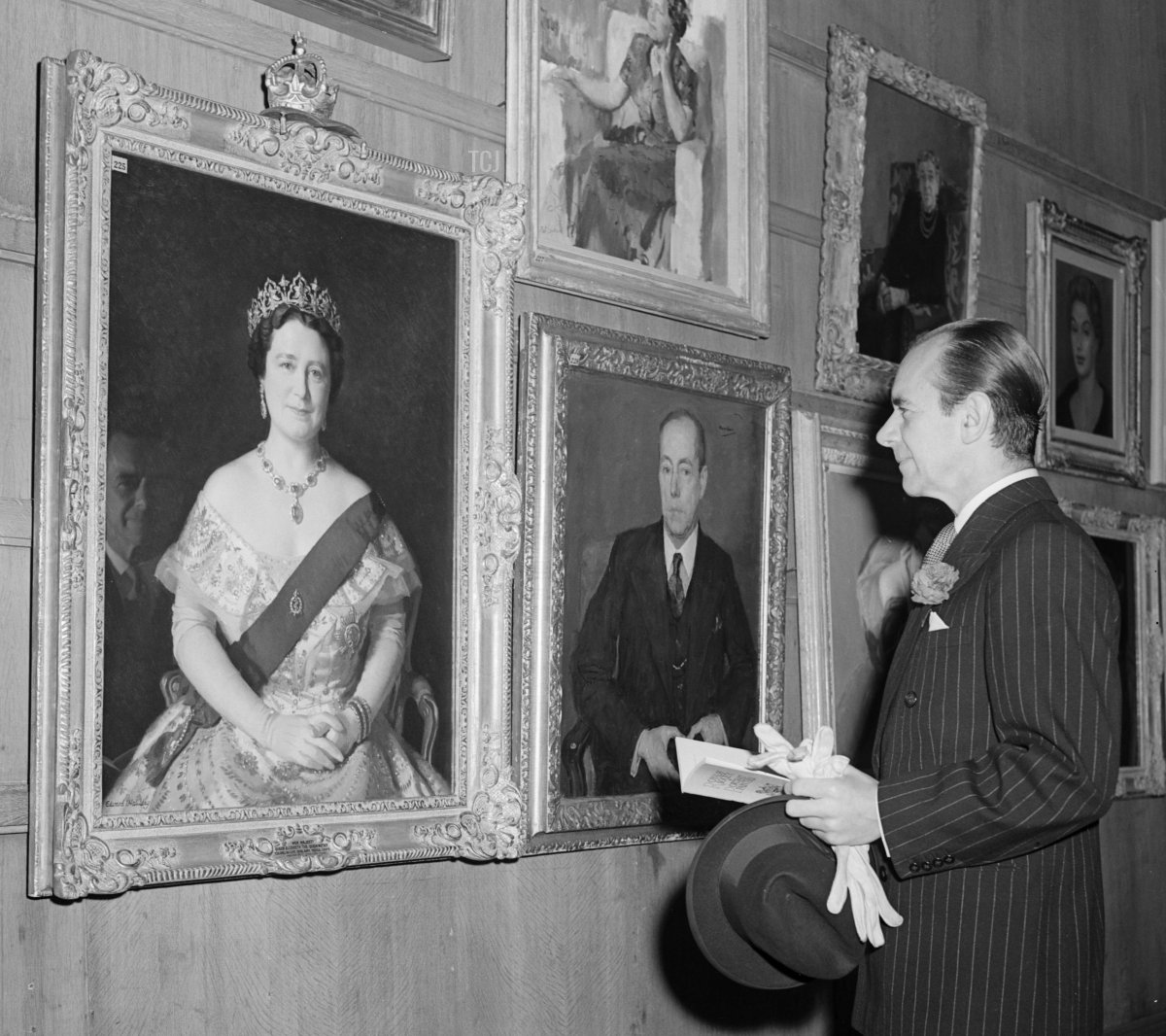 20 novembre 1953: il direttore d'orchestra britannico Malcolm Sargent (1895 - 1967) esamina il ritratto della Regina Madre da Edward I Halliday alla Mostra Annuale della Royal Society of Portrait Painters presso le Gallerie dell'Istituto Reale, Londra