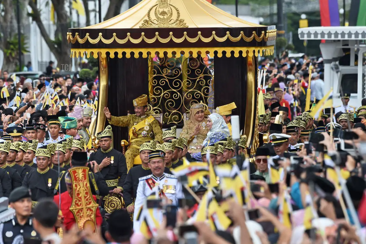 Il sultano del Brunei Hassanal Bolkiah (centro-S) e la regina Saleha (centro-D) salutano dal carro reale durante una processione per celebrare il suo giubileo d'oro di ascesa al trono a Bandar Seri Begawan il 5 ottobre 2017