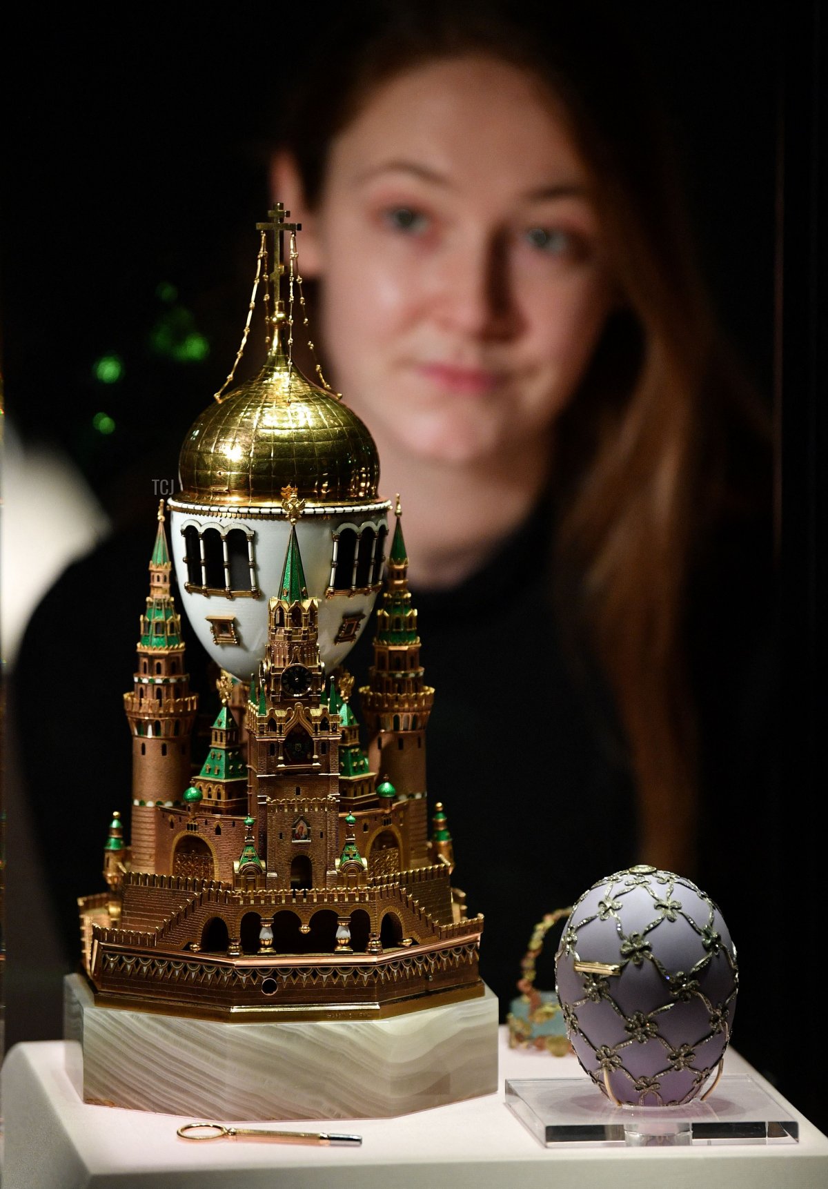 Un assistente alla galleria posa con l' 'Uovo del Cremlino di Mosca' (L) e l' 'Uovo Cigno' durante una photocall per presentare l'esposizione 'Fabergé a Londra: Amore e Rivoluzione', presso il museo V&A (Victoria e Albert) di Londra il 17 novembre 2021