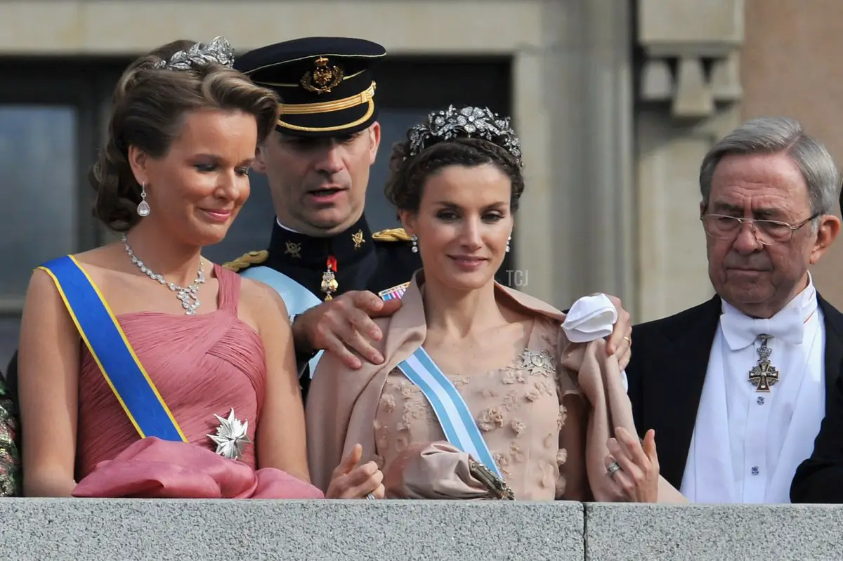 Il Principe Felipe aiuta la Principessa Letizia di Spagna con il suo sciarpone mentre la Principessa Mathilde del Belgio osserva, mentre si trovano sulla terrazza Lejonbacken dopo la cerimonia di matrimonio della Principessa Vittoria e del Principe Daniel di Svezia il 19 Giugno 2010 a Stoccolma, Svezia