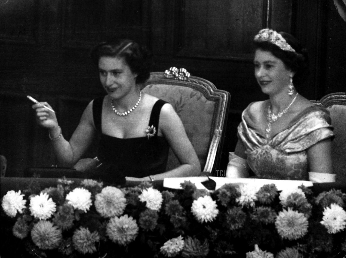 Con gli occhi fissi sul palcoscenico, la Regina Elisabetta II, a destra, e sua sorella, la Principessa Margaret, fumando una sigaretta, osservano lo Spettacolo Varietà Reale dalla Royal Box al Palladium, Londra, 3 novembre 1952