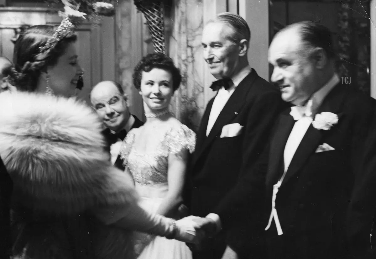 La Regina sorride mentre stringe la mano a Beniamino Gigli, il tenore italiano, mentre attorno a lei si trovano Maurice Chevalier, ballerina americana Nanci Crompton, e Charlie Naughton, al termine dello spettacolo al Palladium, 3 novembre 1952