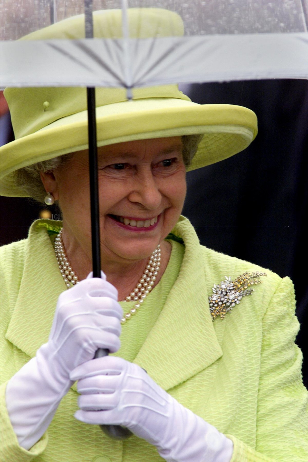 La Regina britannica Elisabetta II, indossando un vestito verde lime e una spilla di diamante wattle, si ripara sotto un ombrello durante la cerimonia ufficiale di benvenuto davanti all'Opera House di Sydney, 20 marzo 2000