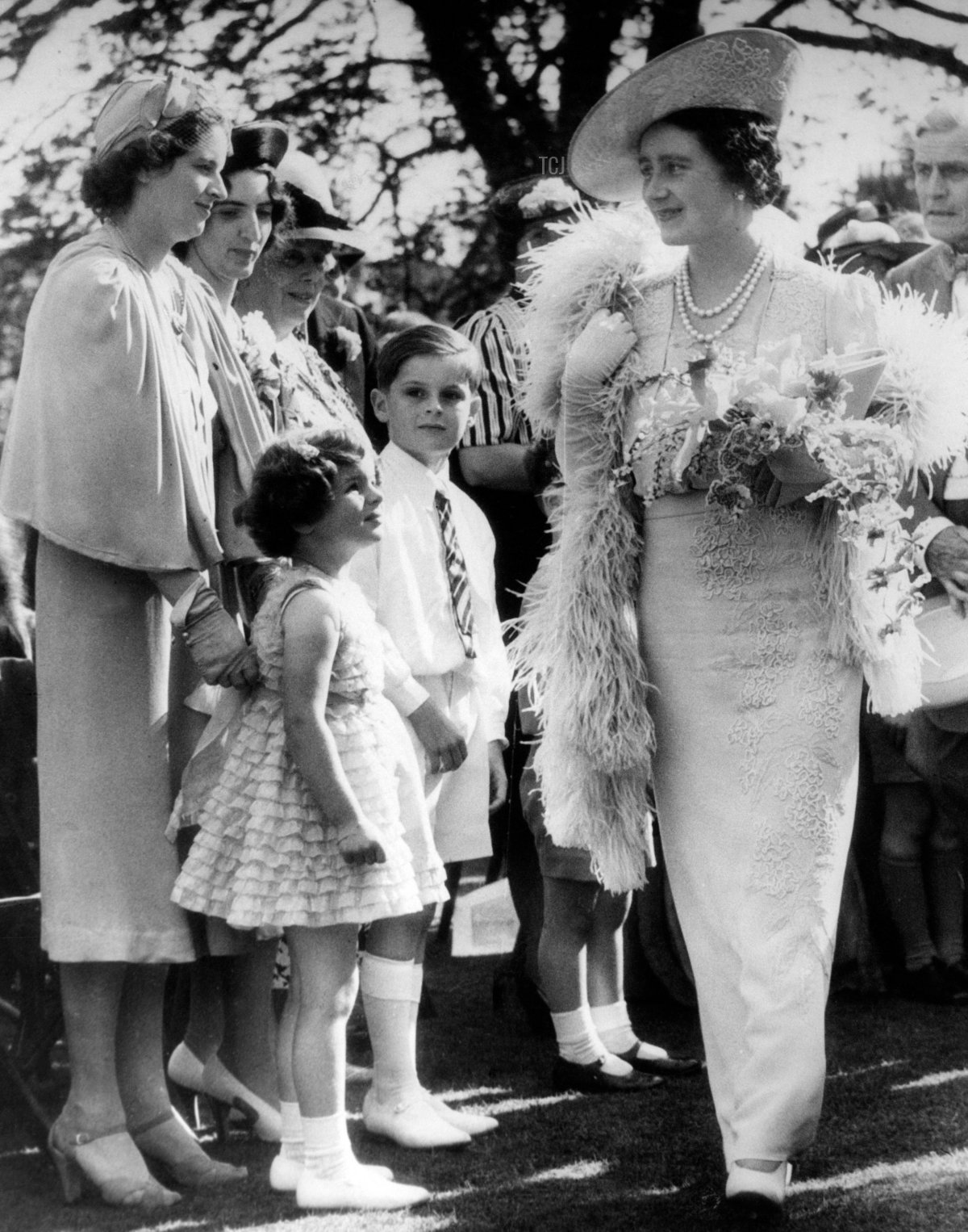 Un piccolo gruppo di persone saluta la Regina Elisabetta al giardino di Mrs. Sigismund Goetze a Grove House, Regents Park a Londra, 25 lug 1939