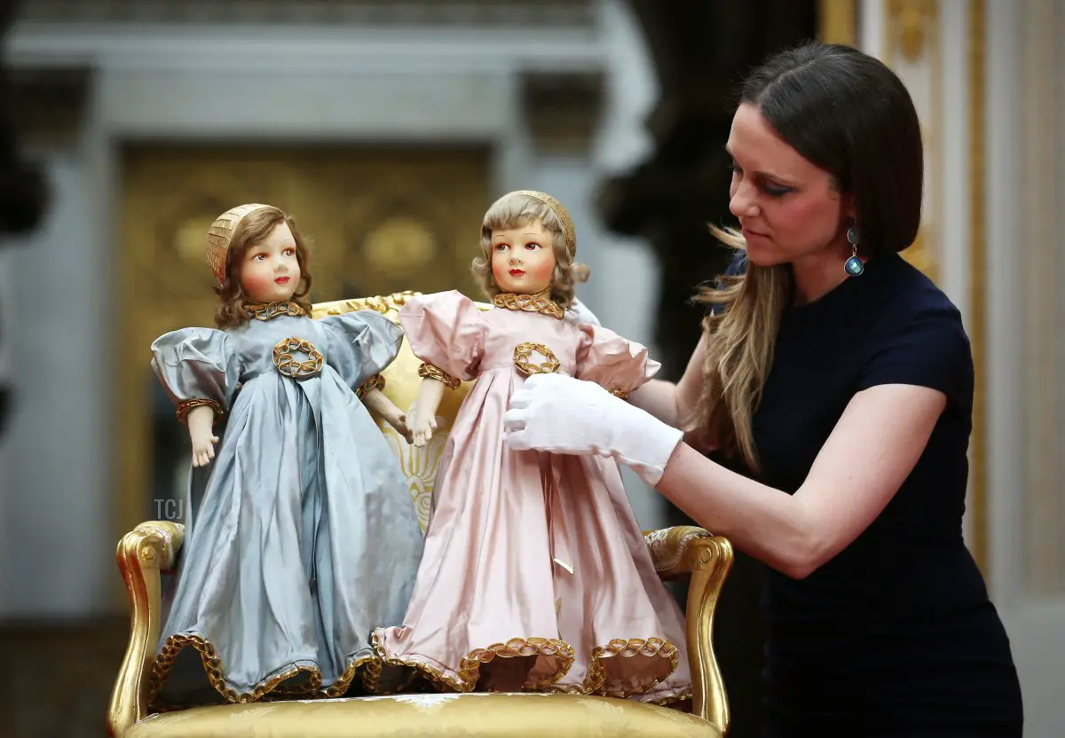 Royal Collection Trust Curator Anna Reynolds adjusts Parisian dolls belonging to Queen Elizabeth II (L) and Princess Margaret at Buckingham Palace ahead of the Royal Childhood exhibition on April 2, 2014 in London, England