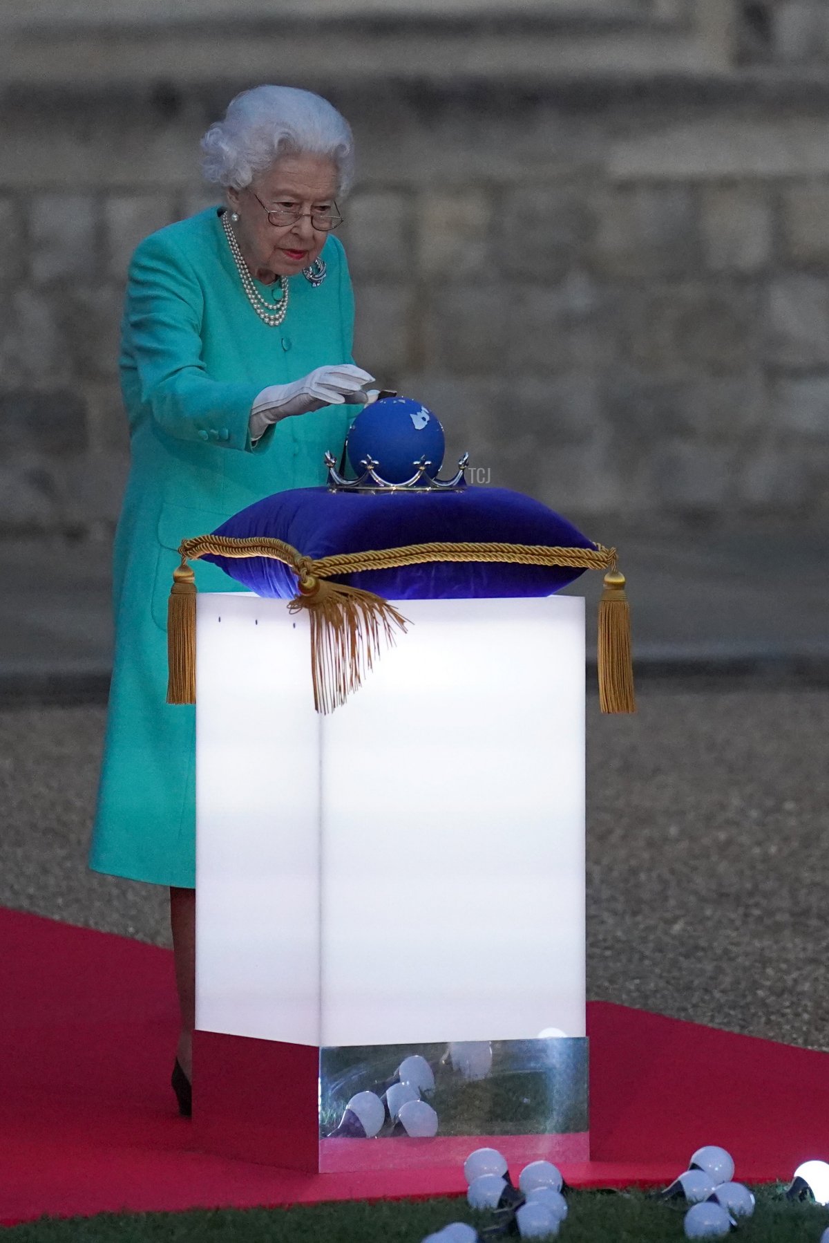 La regina Elisabetta II tocca il Globo delle Nazioni del Commonwealth per avviare l'accensione del Faro Principale davanti al Palazzo di Buckingham a Londra, dal Cortile del Castello di Windsor, a ovest di Londra, il 2 giugno 2022, come parte delle celebrazioni del Giubileo di Platino