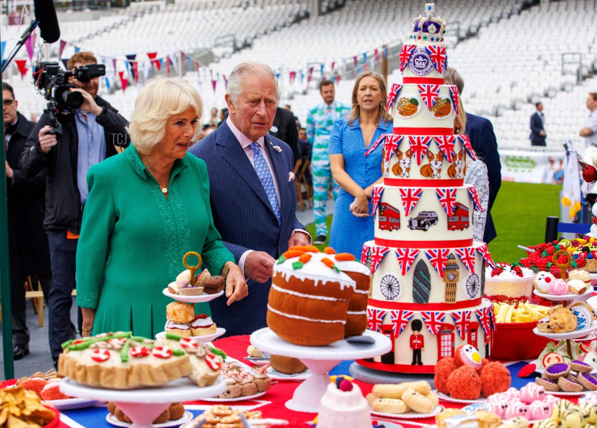 Il principe Carlo d'Inghilterra e Camilla, duchessa di Cornovaglia, ammirano un pezzo d'arte in feltro dell'artista Lucy Sparrow, rappresentante il Platinum Pudding, uova scozzesi e piatti di frutta durante il Big Jubilee Lunch all'Oval di Londra