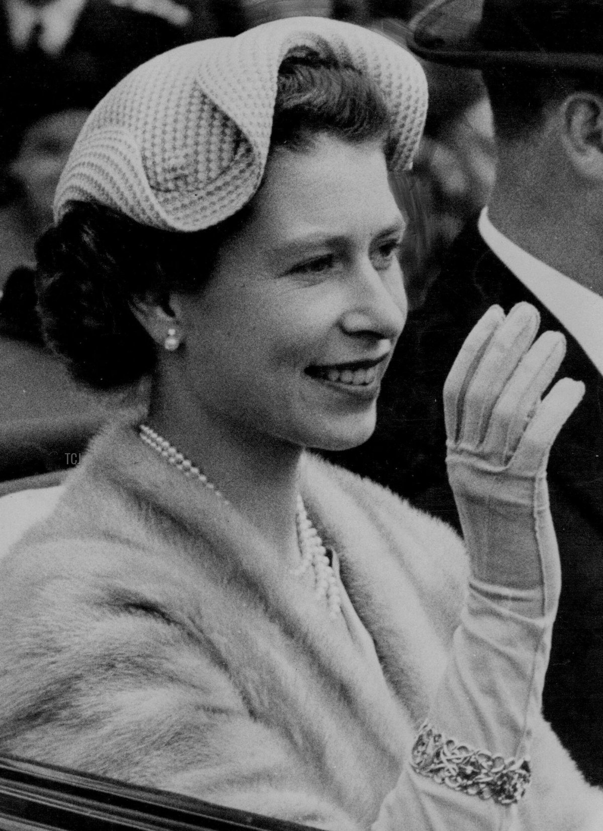 La Regina, sorridente e con un'elegante cappello bianco a onde, percorre la corsia di Ascot con il Duca di Edimburgo nell'ultimo giorno della riunione reale. 18 giugno 1954