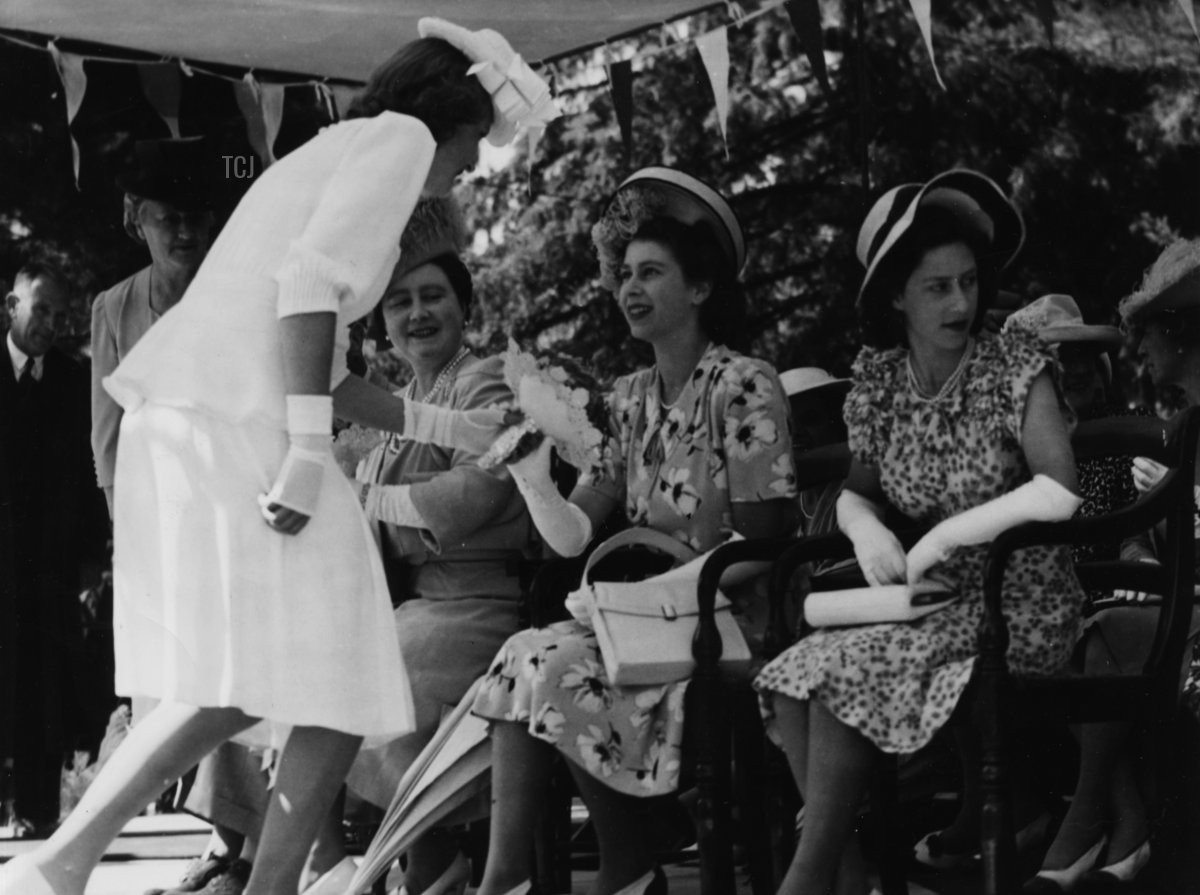 Rene du Preez, figlia del sindaco di Ladybrand, presenta alla Principessa Elisabetta un mazzo di fiori, seduta con sua madre, la Regina Elisabetta e sua sorella, la Principessa Margaret (a destra), nello Stato Libero d'Orange, 19 marzo 1947