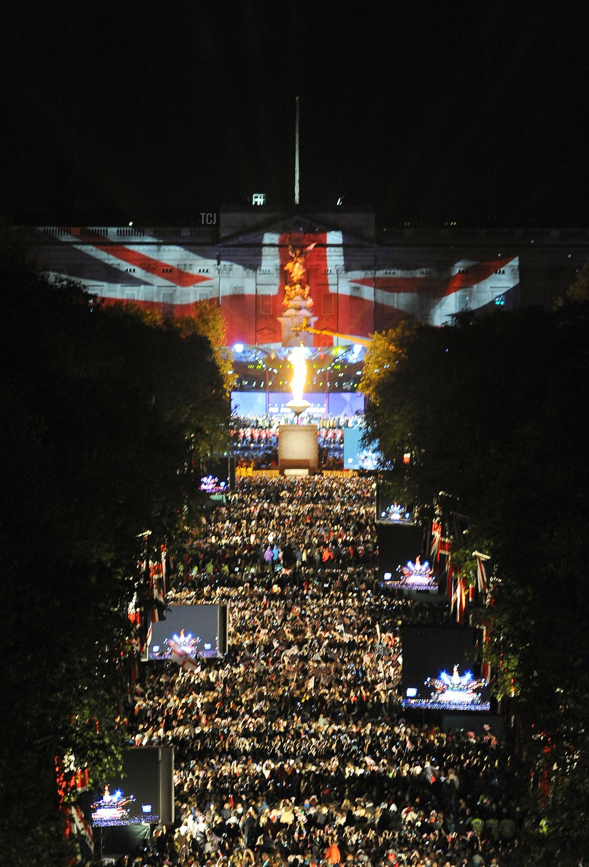 Una torcia (C) viene accesa dalla Regina Elisabetta II durante uno spettacolo pirotecnico all'esterno di Buckingham Palace a Londra, il 4 giugno 2012, per segnare la fine del Concerto del Giubileo di Diamante