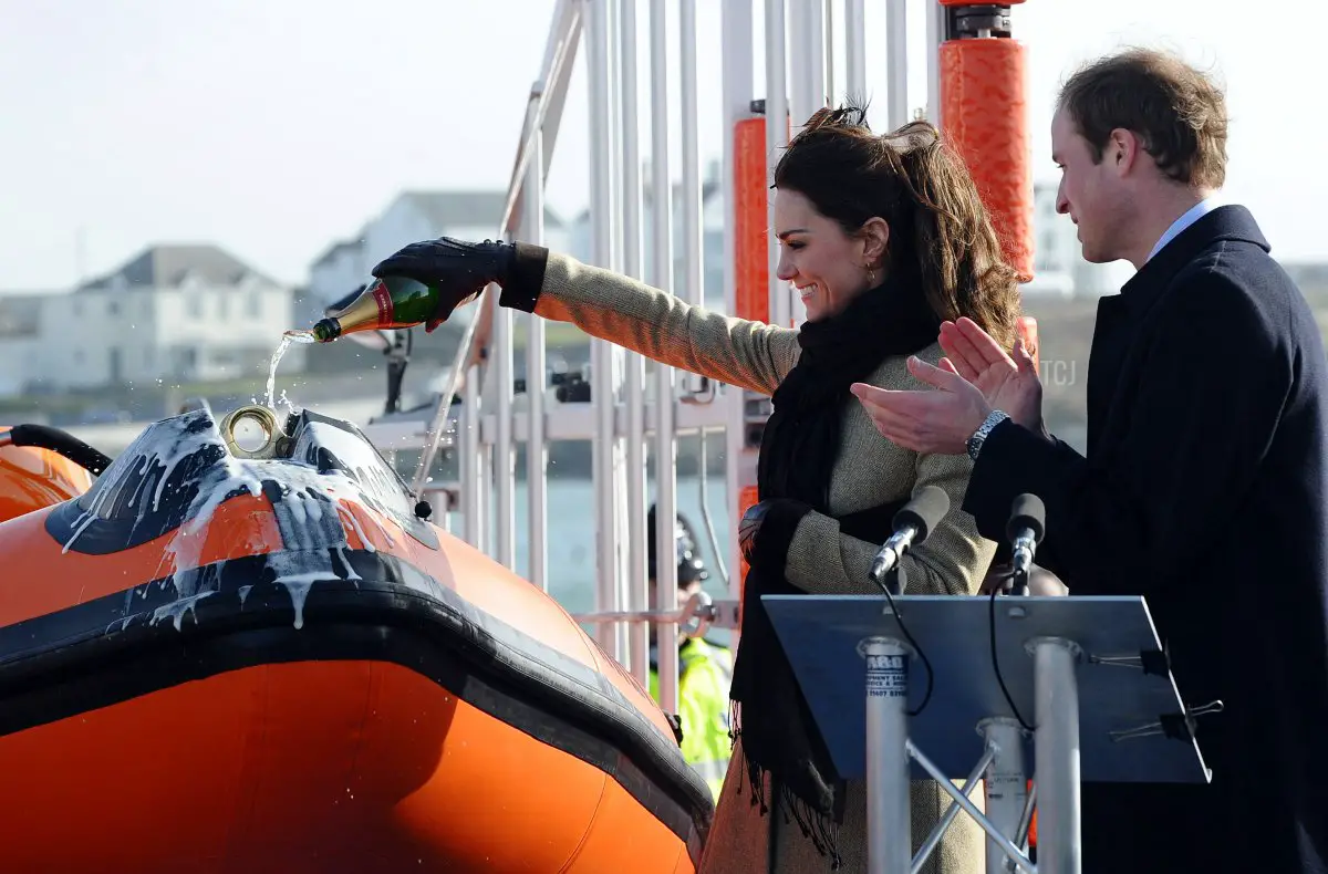 William applaude mentre Kate versa champagne.