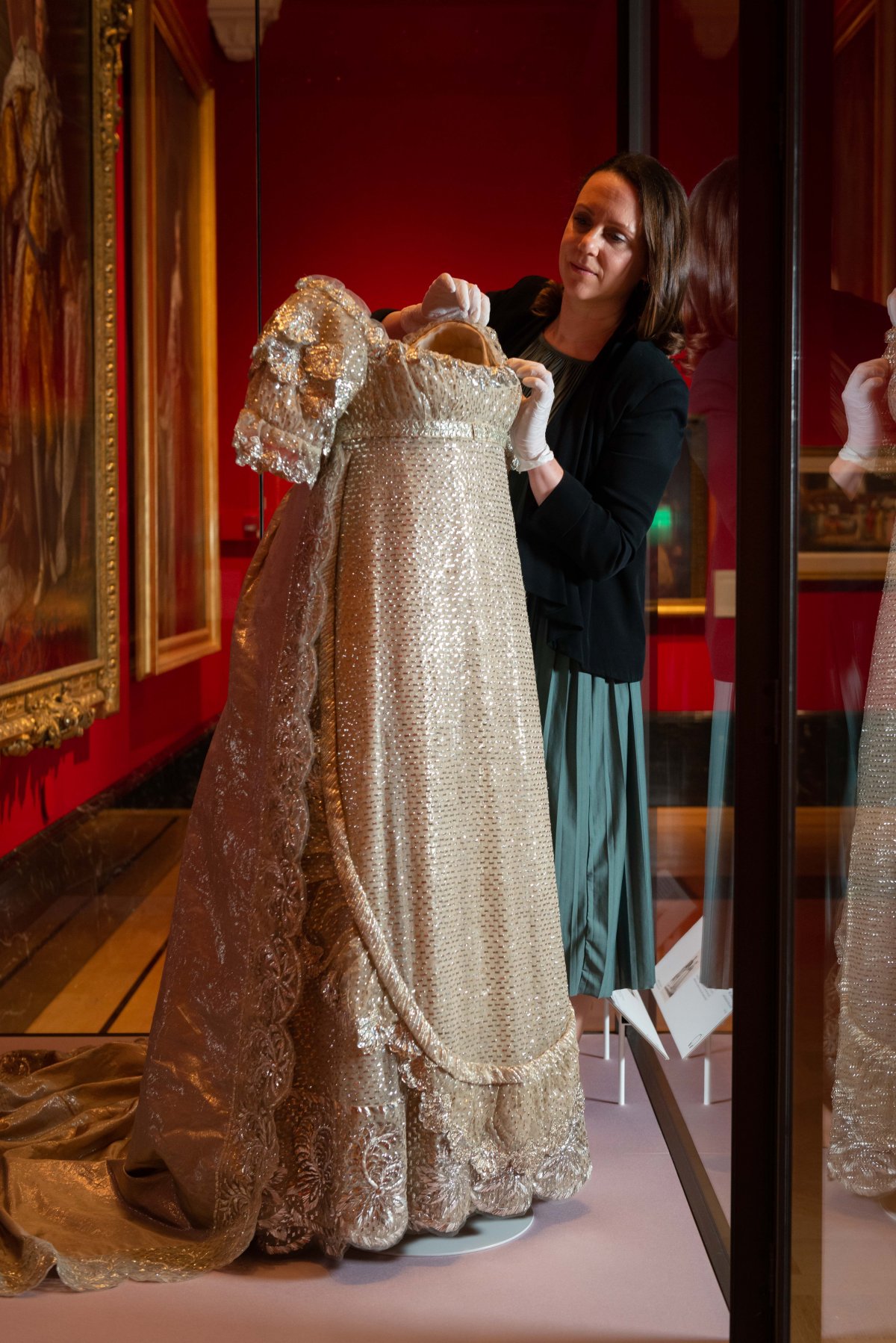 Un curatore regola il vestito da sposa della Principessa Charlotte di Galles (1796-1817), esposto nel 2023 alla Queen's Gallery, Buckingham Palace (Royal Collection Trust)