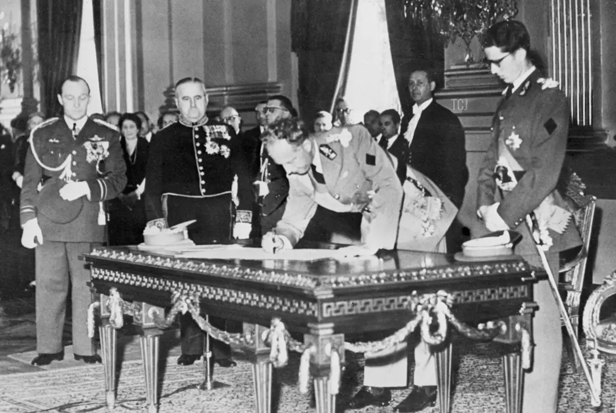 Mentre il Re Baudouin osserva, il Re Leopoldo III del Belgio firma il suo atto di abdicazione presso il Palazzo Reale di Bruxelles il 16 luglio 1951 (AFP tramite Getty Images)