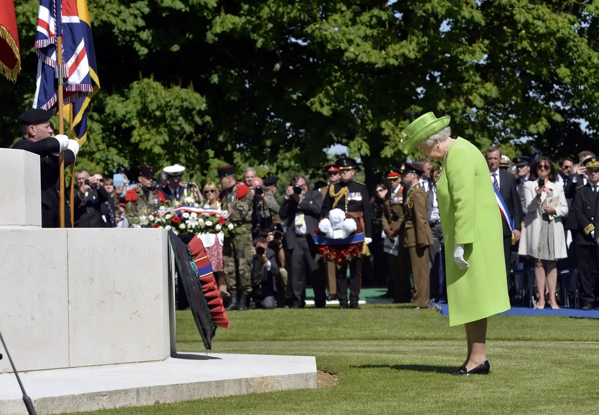 La regina Elisabetta II posa una corona durante una cerimonia di commemorazione bi-nazionale Francia-Regno Unito al Cimitero di Guerra Britannico a Bayeux il 6 giugno 2014 (TOBY MELVILLE/AFP via Getty Images)