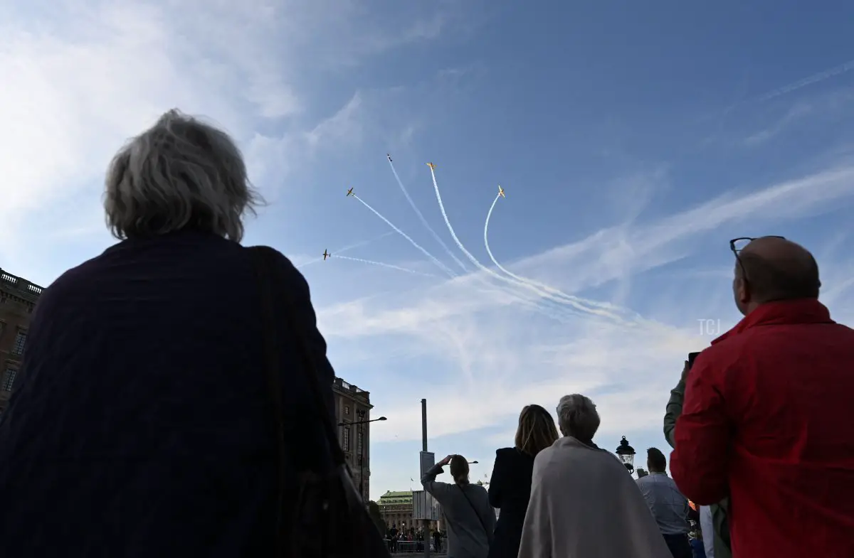 Spettatori osservano i jet in volo sopra il Palazzo Reale durante le celebrazioni del Giubileo d’Oro per Re Carlo XVI Gustavo di Svezia a Stoccolma il 16 settembre 2023 (JONATHAN NACKSTRAND/AFP via Getty Images)