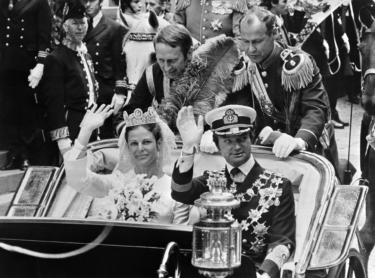 Il Re Carlo XVI Gustaf e la Regina Silvia di Svezia salutano durante una processione in carrozza dopo il loro matrimonio reale a Stoccolma il 19 giugno 1976 (AFP via Getty Images)