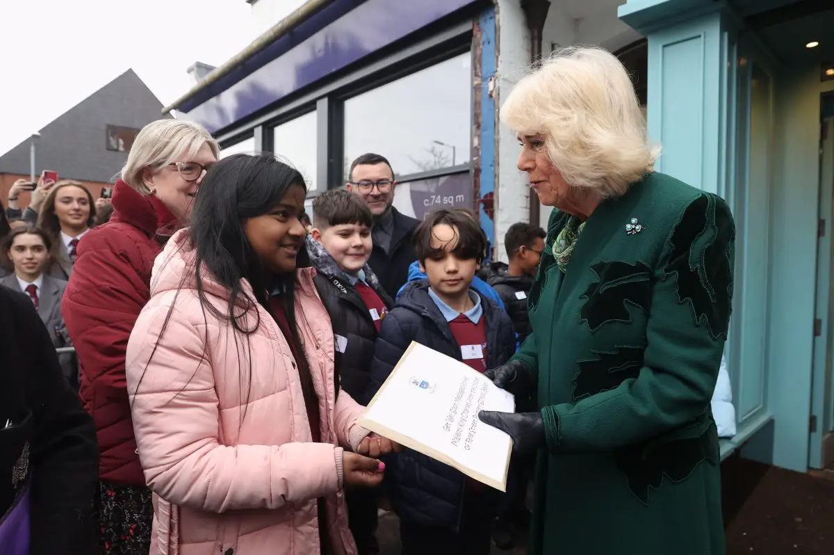 Queen Camilla of the United Kingdom receives a packet of 'Get Well Soon' messages for King Charles from the children of Fane Street Primary School during a visit to Lisburn Road in Belfast on March 21, 2024 (Liam McBurney/PA Images/Alamy)