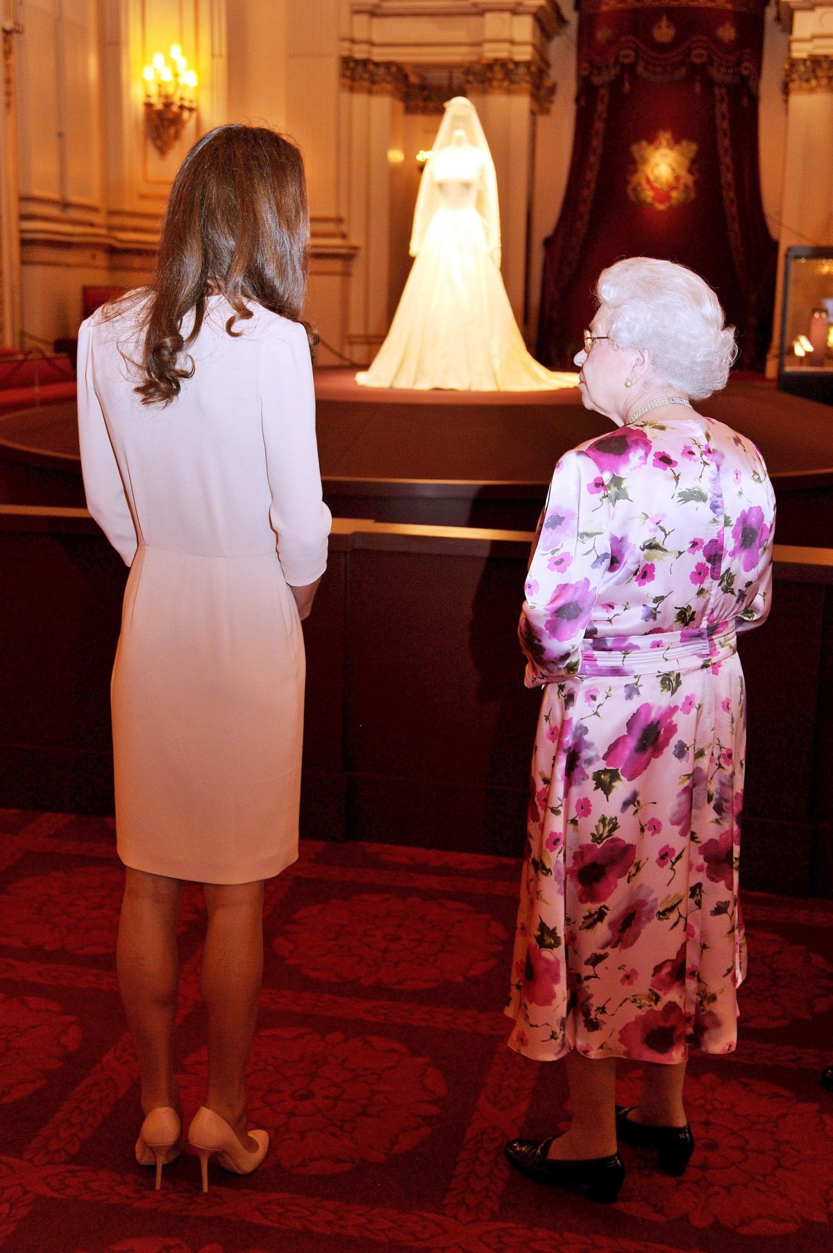 La Duchessa di Cambridge, accompagnando la Regina Elisabetta II, osserva il suo abito da sposa e i gioielli esposti a Buckingham Palace il 22 luglio 2011 (John Stillwell/PA Images/Alamy)