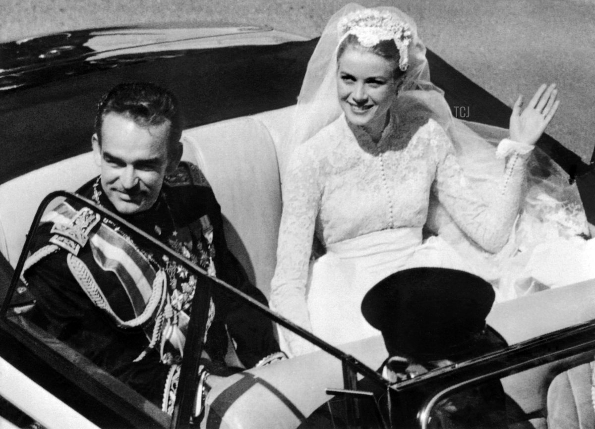 Il Principe Rainier III e la Principessa Grace di Monaco salutano la folla mentre lasciano la Cattedrale di San Nicola in una Rolls Royce cabriolet crema e nera, offerta dal popolo di Monaco come regalo di nozze, dopo la cerimonia nuziale a Monaco il 19 aprile 1956 (AFP via Getty Images)