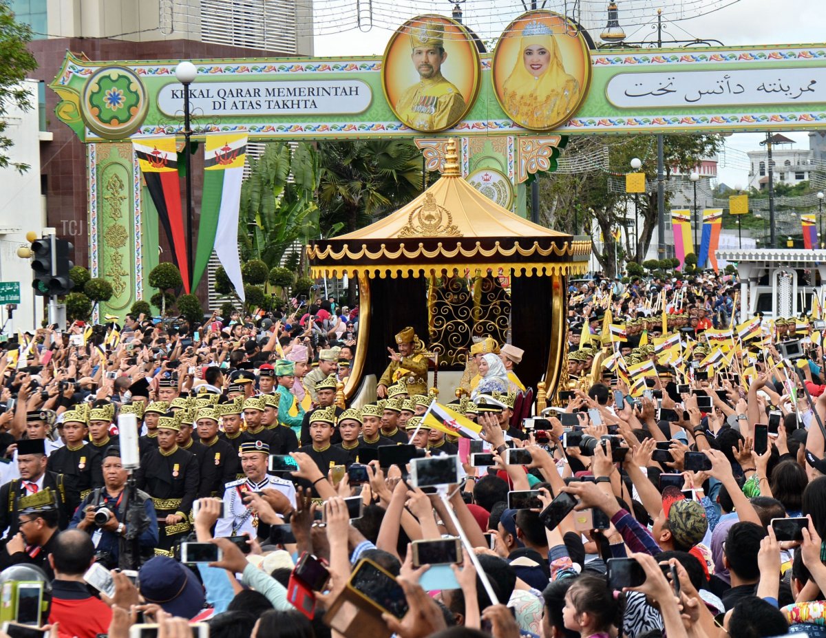 Il sultano del Brunei Hassanal Bolkiah (centro-S) e la regina Saleha (centro-D) salutano dal carro reale durante una processione per celebrare il suo giubileo d'oro di ascesa al trono a Bandar Seri Begawan il 5 ottobre 2017