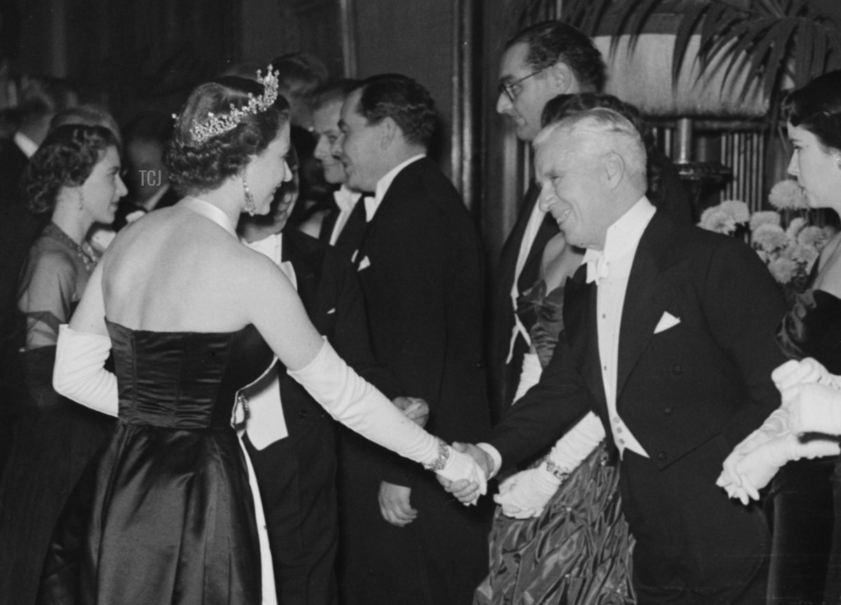 La regina Elisabetta (a sinistra, con una tiara) mentre stringe la mano all'attore Charlie Chaplin durante la fila dopo la proiezione al Royal Film Performance presso l'Empire, Leicester Square, Londra, 27 ottobre 1952